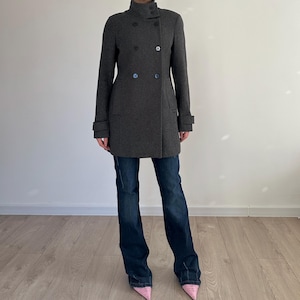 May include: A gray double-breasted coat with a high collar and long sleeves. The coat is made of a soft, textured fabric and has a classic, tailored fit.