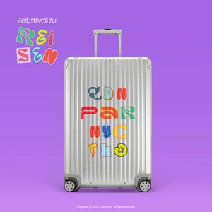 May include: A silver travel suitcase with the words "LDN PAR NYC TKO" in colourful letters. The suitcase has a retractable handle and four wheels. The background is a solid purple colour. The text "Zeit, stilvoll zu Reisen" is also visible.