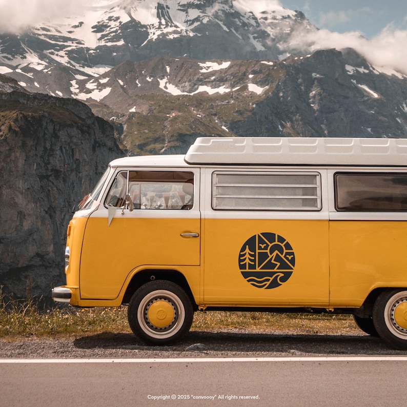 May include: A yellow and white vintage camper van with a black circular graphic on the side, parked on a road with a mountain backdrop. The graphic features trees, a sun, waves, and mountains. The van has a white roof.