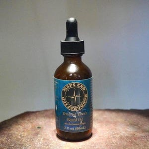 May include: A brown glass bottle of beard oil with a black dropper. The label reads "MAPS END HANDCRAFTED Tempest Tanner Beard Oil" with a compass design. The bottle contains 2 fl oz (56mL) of oil.