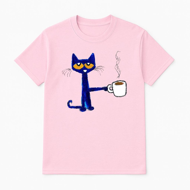 May include: Pink t-shirt with a blue cat holding a cup of coffee. The cat has orange eyes and a white cup with brown coffee.