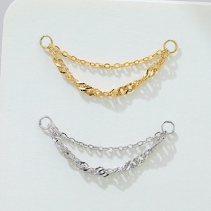 May include: Two chain earrings, one gold and one silver, are displayed against a white background. Each earring features two delicate chains connected by small hoops. The chains have different textures, with one being a classic link and the other a twisted design.