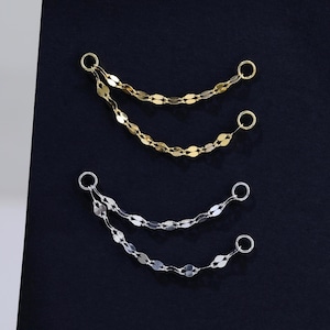 May include: Two decorative jewelry connector chains, one in gold tone and one in silver tone. Each piece consists of two delicate, shimmering linked chains attached to small circular jump rings at both ends, designed for jewelry assembly.
