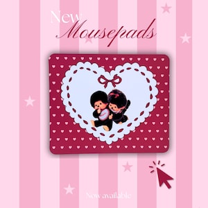 May include: A rectangular mousepad with a burgundy background covered in small white hearts. A white heart-shaped design with a scalloped edge and a bow features two cartoon figures. The text "New Mousepads" and "Now available" are also visible.