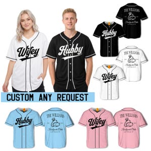 Könnte beinhalten: Eine Kollektion von kurzärmeligen Baseballtrikots mit Knopfleiste in Weiß, Schwarz, Hellblau und Pink. Die Vorderseite zeigt den Schriftzug Wifey oder Hubby in schwarzer oder weißer Schreibschrift. Die Rückseite zeigt den Text The Williams, Est. 2020, Newlyweds Club, Las Vegas, NV und eine Ringgrafik.