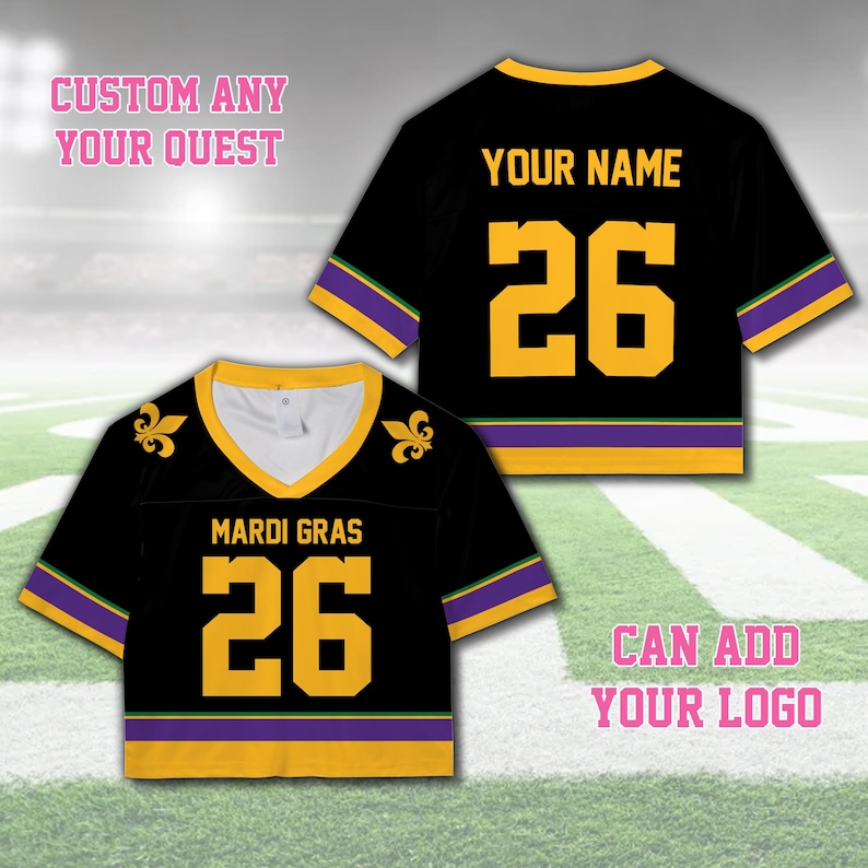 Pode incluir: Camisola preta com letras e acabamentos dourados. A camisola tem decote em V e apresenta o n&uacute;mero 26. O texto "MARDI GRAS" &eacute; exibido na frente. A camisola tamb&eacute;m tem o texto "YOUR NAME" nas costas. A camisola tem detalhes roxos e verdes.