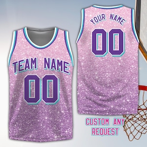 May include: A pink glitter basketball jersey with the text "TEAM NAME" and the number "00" on the front. The back of the jersey has the text "YOUR NAME" and the number "00". The jersey has teal and white trim. The text "CUSTOM ANY REQUEST" is at the bottom.