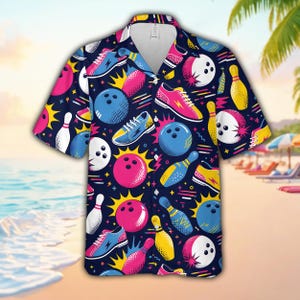 Könnte beinhalten: Ein kurzärmeliges, dunkelblaues Hemd mit Knopfleiste und einem sich wiederholenden Muster aus rosa, blauen und weißen Bowlingkugeln, gelben und weißen Kegeln sowie bunten Bowlingschuhen mit Blitzmotiven auf einem dunklen Hintergrund.
