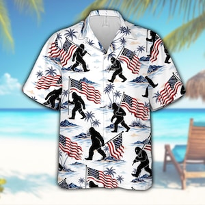Könnte beinhalten: Weißes kurzärmeliges Hemd mit einem sich wiederholenden Muster aus schwarzen Bigfoot-Figuren, die amerikanische Flaggen tragen. Das Design umfasst rot-weiß-blaue Flaggen, Palmen und eine Strandszene. Das Hemd hat einen klassischen Kragen und eine lockere Passform.