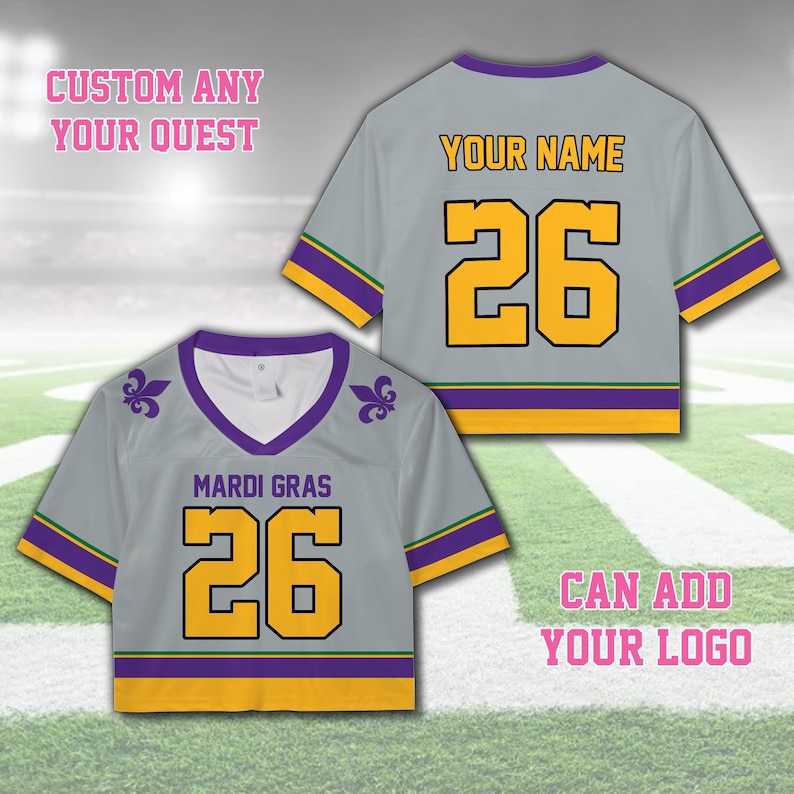 Pode incluir: Duas blusas cinzentas com o texto "MARDI GRAS" e "YOUR NAME" em amarelo. As blusas t&ecirc;m decote em V e mangas curtas com detalhes roxos e dourados. O n&uacute;mero "26" &eacute; exibido em amarelo em ambas as blusas. O texto "CUSTOM ANY YOUR QUEST" e "CAN ADD YOUR LOGO" tamb&eacute;m s&atilde;o vis&iacute;veis.
