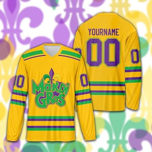 May include: A yellow long-sleeved jersey with green and purple stripes and accents. The front features the text "Mardi Gras" in green and a purple fleur-de-lis. The back displays the number "00" in purple and the name "YOURNAME".