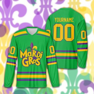 May include: Green long-sleeved jersey with gold and purple accents. The front features the words "Mardi Gras" in yellow with a purple fleur-de-lis. The back has the word "YOURNAME" above the number "00" in gold. The sleeves have the number "0" and "10".