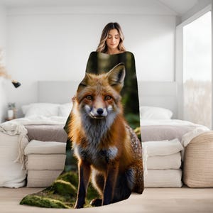 May include: A soft, plush throw blanket featuring a close-up image of a red fox with a white chest and a lush green forest background.