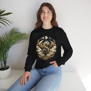 May include: Black sweatshirt with a gold dragon design, surrounded by clouds and moons. The dragon is in a circle with a crescent moon and stars.