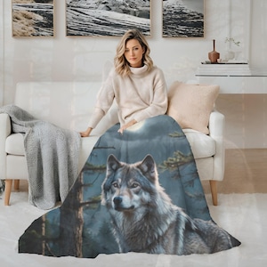 Op de afbeelding: Een zachte plaid met een gedetailleerde, realistische illustratie van een grijze wolf in een bosrijke omgeving. De wolf is afgebeeld met dikke vacht in tinten grijs, wit en bruin, tegen een achtergrond van donkere bomen en een maanverlichte lucht.
