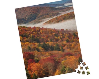 May include: A panoramic view of a forested valley in autumn. The trees are a mix of red, orange, yellow, and green. A layer of fog covers the valley floor, creating a dreamy atmosphere.