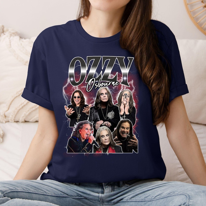 Puede incluir: Camiseta azul marino con un gr&aacute;fico de Ozzy Osbourne y el texto "OZZY Osbourne" en fuente plateada met&aacute;lica. El gr&aacute;fico incluye m&uacute;ltiples im&aacute;genes del m&uacute;sico con un fondo de rayos rojos y blancos.