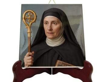 May include: A framed portrait of a woman in a black habit, holding a gold staff. The portrait is displayed on a dark red wooden easel. The woman is looking forward, with a book tucked under her arm.