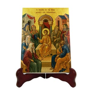 Puede incluir: Icono religioso que representa una escena con figuras con túnicas doradas, rojas, azules y verdes. El icono está montado sobre un soporte de madera marrón oscuro. El texto de la imagen está en griego.