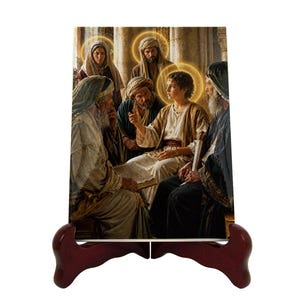 Puede incluir: Una impresión de obra de arte religiosa que representa una escena bíblica de un joven hablando con un grupo de hombres mayores. La impresión se muestra en un caballete de madera marrón oscuro. La obra de arte presenta tonos cálidos y halos dorados.