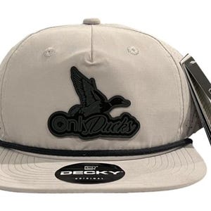 May include: A gray and black baseball cap with a black duck logo and the text "Only Ducks". The cap has a black rope trim and a black "DECKY ORIGINAL" label.