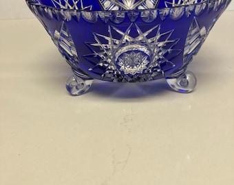 May include: A blue glass bowl with a cut glass design and three feet. The bowl has a starburst pattern.