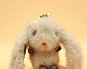 May include: A fluffy gray bunny keychain with brown leather boots. The bunny has long, soft ears and a sweet expression.