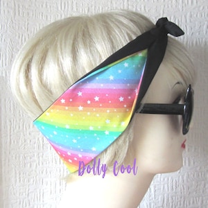 May include: A rainbow and white star patterned headband with a black tie. The headband is tied around a mannequin's head.