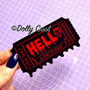 May include: A black and red sticker in the shape of a ticket with the word "HELL" in dripping red letters. The sticker also says "ONE WAY" and "ADMIT ONE". A devil face is on the right side of the ticket.