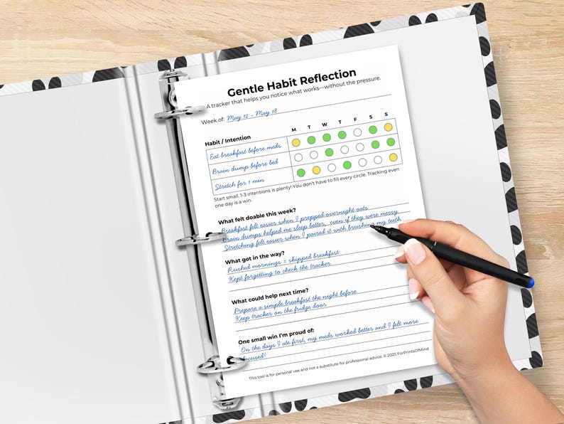 A realistic binder mockup showing a filled-in Gentle Habit Reflection sheet. Entries include “Eat breakfast before meds” and notes on what got in the way, what helped, and a small win.