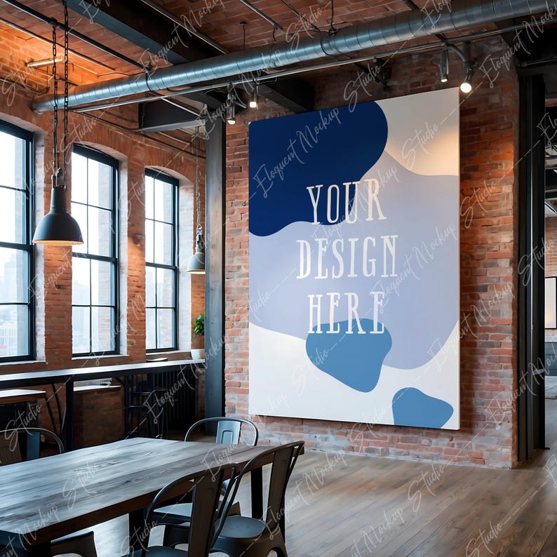 Op de afbeelding: Een witte canvas mockup met blauwe en grijze abstracte vormen en de tekst "YOUR DESIGN HERE" in een moderne loft met bakstenen muren en een houten vloer.