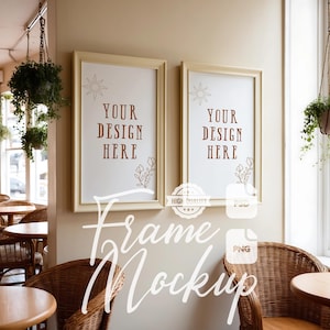 May include: Two white picture frames with a cream colored mat, hanging on a beige wall. The frames are empty and have the text "Your Design Here" in brown text. The frames are in a cafe setting with wicker chairs and tables.