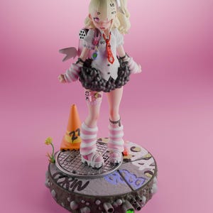 May include: A pink and white anime figurine with black hair and a white bow. The figurine is wearing a white shirt with a red tie, a black skirt, and pink and white striped socks. The figurine is standing on a gray and black base with a yellow traffic cone and green plants.