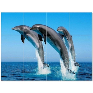 May include: Three gray dolphins leap out of the water, creating splashes of blue water. The dolphins are in mid-air, with their tails and fins extended. The background is a bright blue sky.