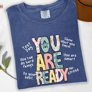 May include: Denim blue t-shirt with the words "YOU ARE READY" in colorful, patterned letters. Additional text includes "Test Day," "You can do hard things," and "Show what you know."
