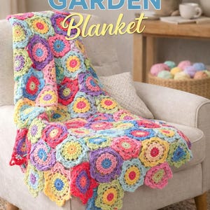 Op de afbeelding: Een kleurrijke gehaakte deken met bloemmotief, gedrapeerd over een beige fauteuil. De deken toont een mix van kleuren zoals roze, geel, blauw en paars. De afbeelding bevat de tekst "COLORFUL GARDEN Blanket" en "CROCHET PATTERN".