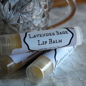 以下が含まれることがあります： 黒い文字で書かれたラベンダーセージリップバームの白いチューブが3本。ラベルには「Lavender Sage Lip Balm」と「net wt. .15 oz/4g」と書かれています。