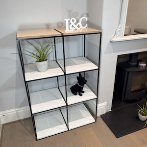 May include: A black metal shelf unit with six white shelves. The shelf unit has a wooden top and is decorated with a white wooden sign that says "I & C".