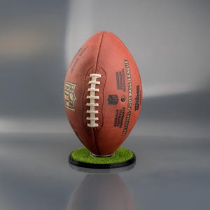 NFL football display stand with a sturdy black base, designed to hold and showcase a full-size American football vertically or horizontally, ideal for sports memorabilia display.