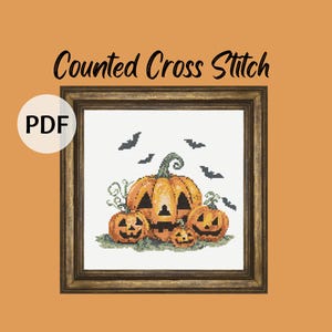 Puede incluir: Un patrón de punto de cruz enmarcado con un grupo de calabazas naranjas con caras talladas, rodeadas de vides verdes y murciélagos negros. El texto "Counted Cross Stitch" está encima de la imagen, y un icono "PDF" está en la esquina.