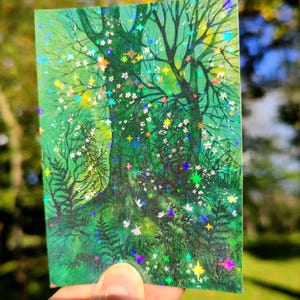 May include: A rectangular sticker featuring a vibrant illustration of a forest scene. The artwork showcases a large tree with intricate branches, surrounded by lush greenery and white flowers. The image is embellished with colorful, sparkling accents.