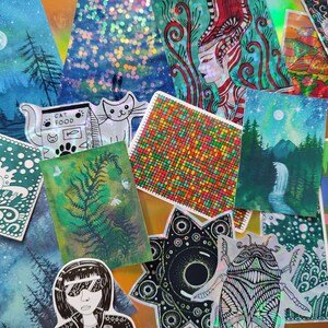 May include: A collection of colorful art prints and stickers. The prints feature various designs, including landscapes with trees and waterfalls, a cat, a fern, and a woman with sunglasses. The stickers include a toucan and a geometric design.