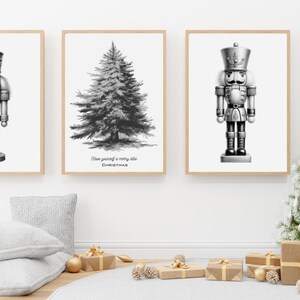 May include: Three black and white illustrations in frames. The left and right frames feature a nutcracker soldier. The center frame features a Christmas tree with the text "Now you're off to a merry little Christmas".