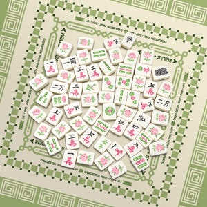 K&ouml;nnte beinhalten: Eine Sammlung wei&szlig;er Mahjong-Steine mit roten und gr&uuml;nen chinesischen Schriftzeichen und rosa Blumendesigns. Die Steine liegen auf einem gr&uuml;nen und beigen Spielbrett mit dekorativen R&auml;ndern und dem Text "Charleston Right Over Left".
