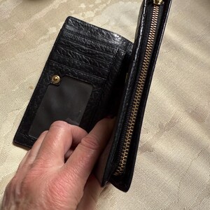 May include: Black leather wallet with a gold zipper and a clear plastic window for an ID card.