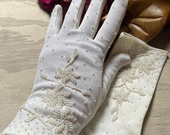 May include: A pair of white gloves with pearl beading and floral embroidery. The gloves are made of a soft, stretchy fabric and have a delicate, feminine look.