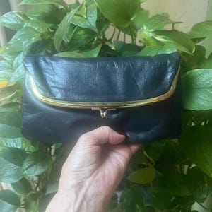 Pu&ograve; includere: Una pochette in pelle blu scuro con una chiusura in metallo dorato.