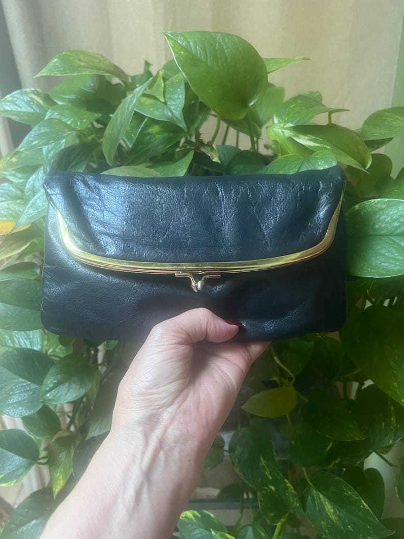 Pu&ograve; includere: Una pochette in pelle blu scuro con una chiusura in metallo dorato.