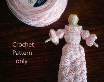 Puede incluir: Un vestido de crochet rosa con un patrón floral. El vestido está hecho con hilo DMC Cébélia 50g en color 818, talla 30. El vestido está en una muñeca con cabello rubio.