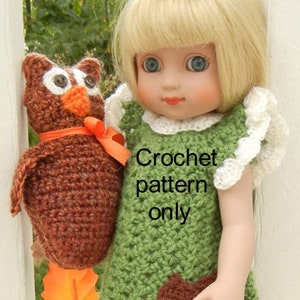 May include: A crocheted green dress with white trim and a brown acorn applique. The dress is being worn by a doll with blonde hair and blue eyes. The doll is holding a crocheted brown owl. The text "Crochet pattern only" is visible on the image.